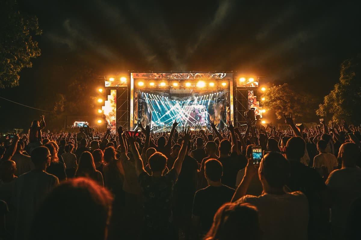 Outdoor festival stage at night, crowd seen from behind