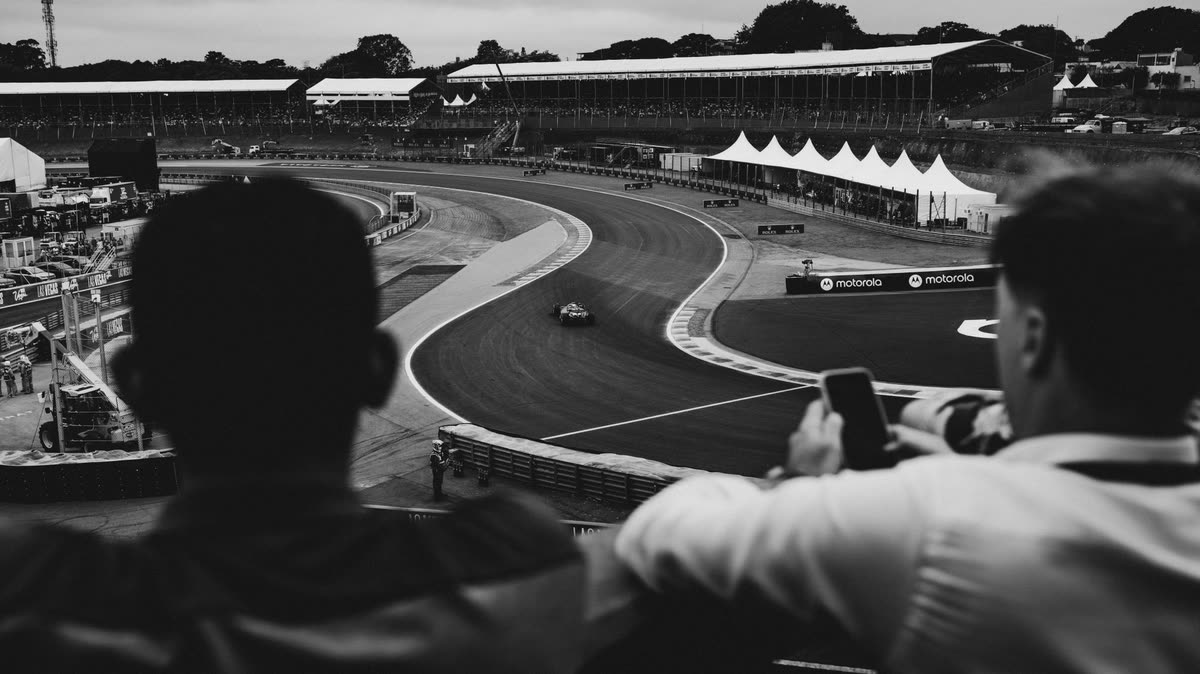 Spectators watching cars on a racing circuit, black and white